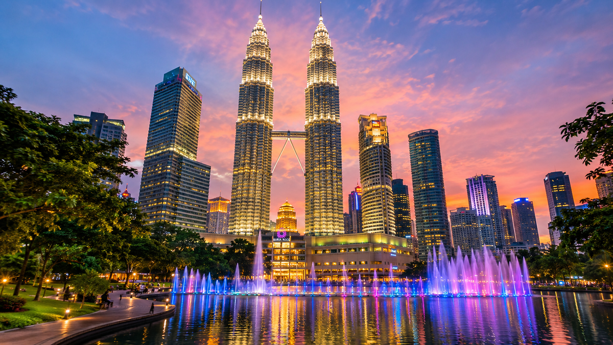 The Petronas Twin Towers lit up at dusk above the KLCC park fountain, Kuala Lumpur