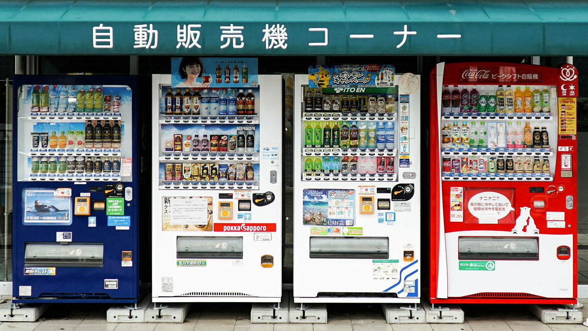 A row of Japanese street vending machines stocked with cold drinks